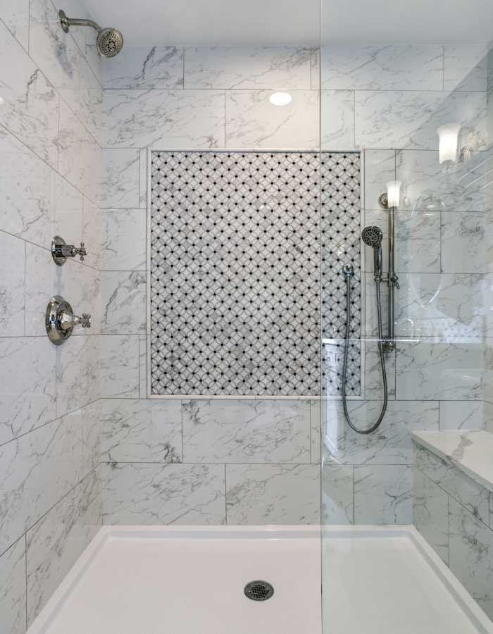 Modern bathroom with a glass-enclosed shower, marble-patterned tiles, and a decorative accent wall, showcasing a sleek and clean design